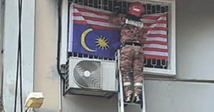 Fireman removes upside down Jalur Gemilang at Batu Caves shop